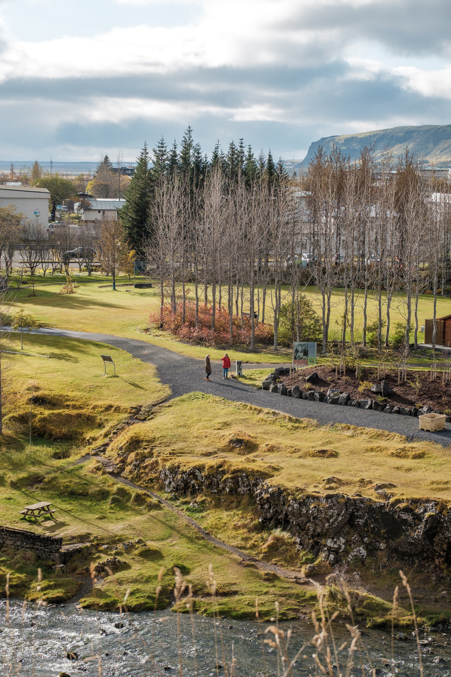 Two people walk through Hveragerði's tiny park